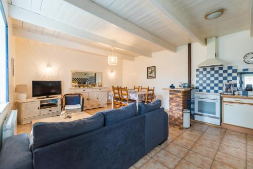 a living room with a blue couch and a kitchen at La Maison Bleue - 300m de la mer in Pleubian