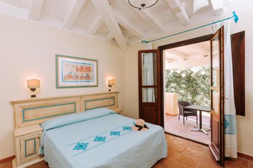1 dormitorio con cama, mesa y espejo en Valtur Baia dei Pini en Budoni