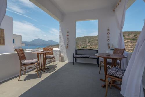 uma varanda com mesas e cadeiras e vista para o oceano em moments rooms em Adamas