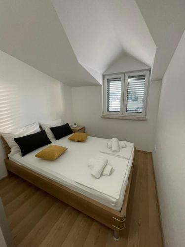 a bedroom with a large white bed with a window at Apartments Holiday Gavric in Trogir