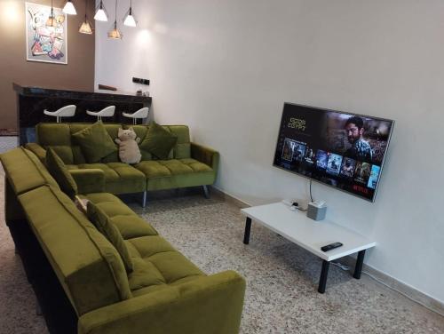 a living room with two couches and a flat screen tv at Batu Pahat Taman Banang Homestay in Batu Pahat