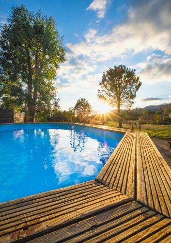 - une piscine avec une terrasse en bois et le coucher du soleil dans l'établissement Domaine Pedra Llampada Gîte Mer, à Villelongue-dels-Monts