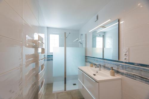 Baño blanco con lavabo y espejo en Domaine Pedra Llampada Gîte Mer, en Villelongue-dels-Monts