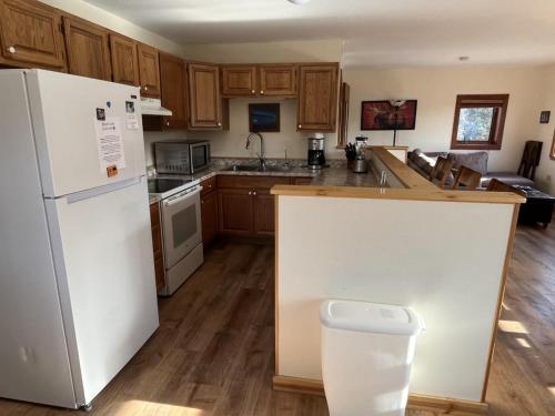 a kitchen with a white refrigerator and wooden cabinets at Denali Park View House in Healy