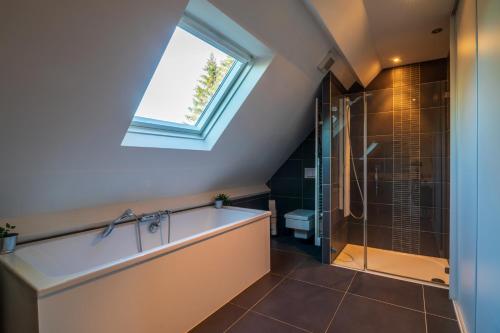 a bathroom with a bath tub and a window at Loft les deux cèdres avec vue panoramique in Charleville-Mézières