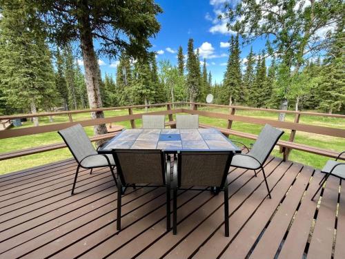 a wooden deck with a table and chairs on it at Denali Natl Park 3 Bedroom Home on 5 Acres, hiking and wildlife in Healy