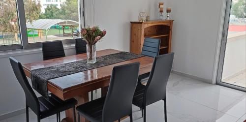 a dining room with a wooden table and black chairs at Ellas Modern Duplex City Center in Nicosia