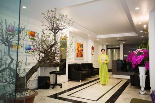 Una mujer está parada en un vestíbulo con flores. en My Linh Hotel, en Hanói