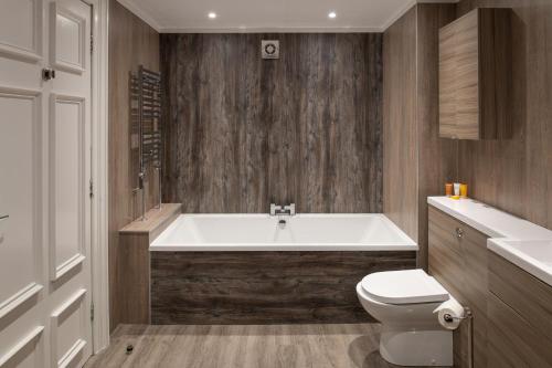 a bathroom with a white tub and a toilet at Fairfield House Hotel in Ayr