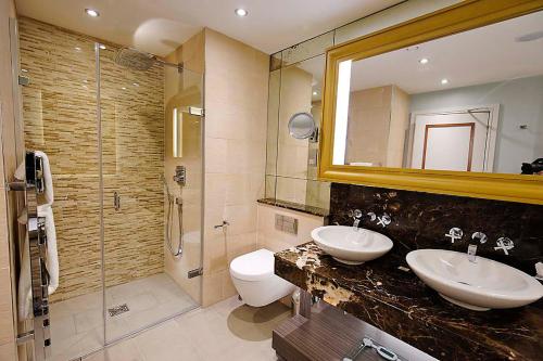 a bathroom with two sinks and a shower and a mirror at Grosvenor Pulford Hotel & Spa in Pulford
