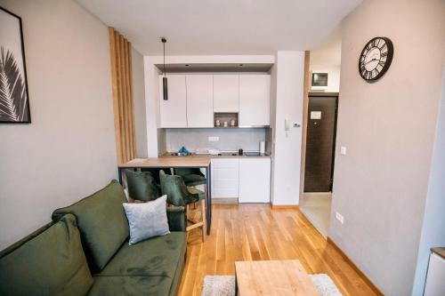 a living room with a green couch and a kitchen at EVA apartman, Titova Vila, Zlatibor in Palisad