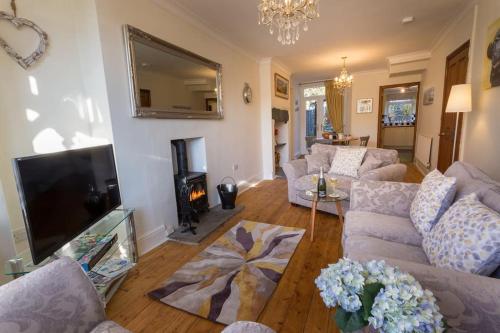 uma sala de estar com sofás e uma televisão em Holly Cottage em Bowness-on-Windermere