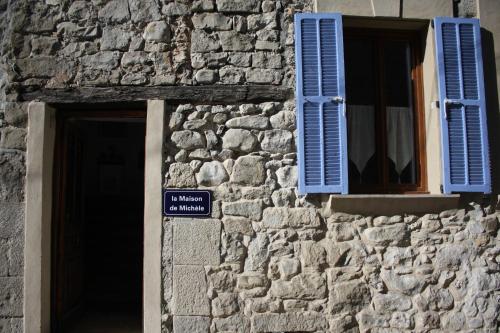 a stone building with a window and blue shutters at La Maison de Michele in Le Fugeret
