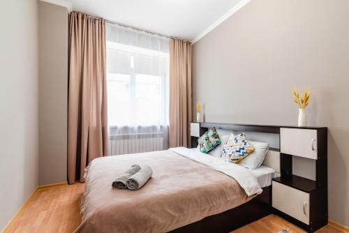 Un dormitorio con una cama grande y una ventana en В спокойном районе в центре города - 2 комнатная en Almaty