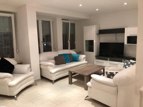a living room with white furniture and a table at Ferienwohnung Amperblick Fürstenfeldbruck in Fürstenfeldbruck