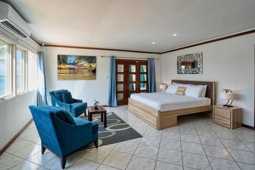 a bedroom with a bed and two blue chairs at Private Beach Ocean Front Boat Dock Tiki Bar in Savaneta