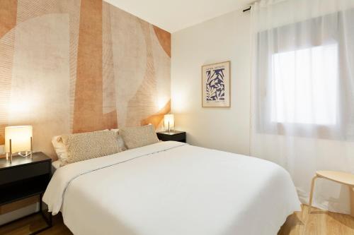 - une chambre avec un grand lit blanc et une fenêtre dans l'établissement Urban Chill Apartments by Olala Homes, à L'Hospitalet de Llobregat