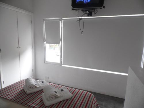 Un dormitorio con toallas en una cama con televisión. en Valeria City, en Valeria del Mar