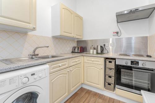エディンバラにあるBright and Quiet Edinburgh Homeの白いキャビネット、シンク、食器洗い機付きのキッチンが備わります。