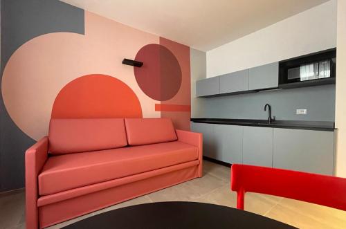 a living room with a red couch and a kitchen at Arqué Apartments - Arco Centro in Arco