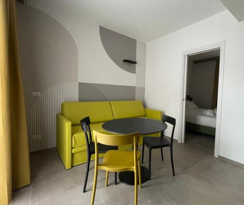 a table and chairs and a yellow couch in a room at Arqué Apartments - Arco Centro in Arco
