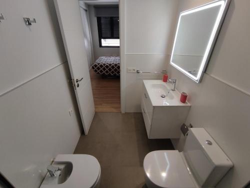 y baño con aseo, lavabo y espejo. en Apartamento Alfareria de Triana - Kainga Homes, en Sevilla