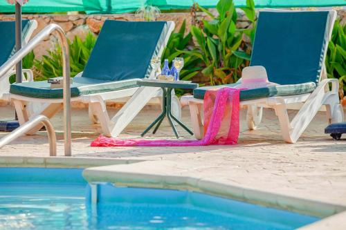 two chairs and a table next to a swimming pool at Villa Styliani in Argaka