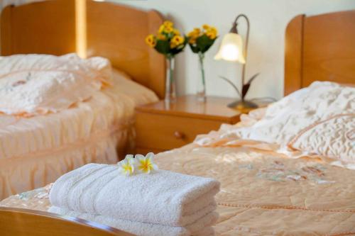 two beds with towels and flowers on a table at Villa Styliani in Argaka