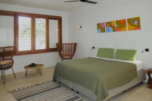 a bedroom with a bed and some chairs and windows at Caribbean Oceanview Villa in Kralendijk