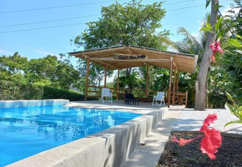 a swimming pool with a wooden pergola next to a house at L'Oasis Don Juan in Don Juan