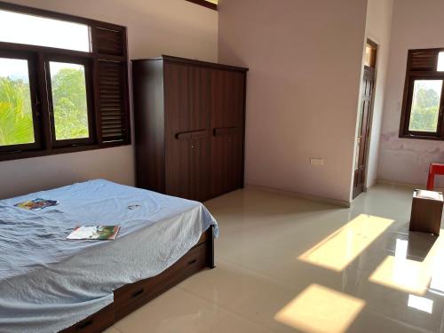 ein Schlafzimmer mit einem Bett in einem Zimmer mit Fenstern in der Unterkunft Hilltop Palace Elpitiya in Elpitiya