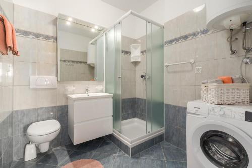 a bathroom with a toilet sink and a washing machine at Marisol Premium - fußläufig zum Meer in Funtana