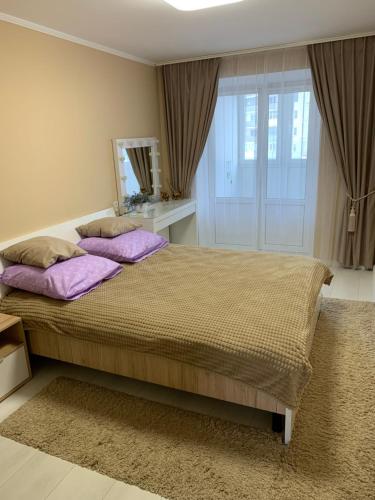 ein Schlafzimmer mit einem großen Bett mit lila Kissen in der Unterkunft Апартаменты LUXURY in Berdychiv