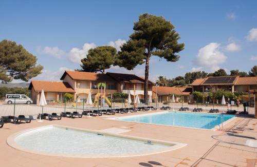 Una piscina en un complejo con sillas y árboles. en Azureva La Londe les Maures, en La Londe-les-Maures