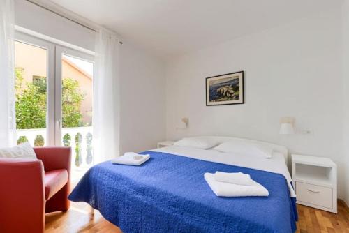 a white bedroom with a blue bed and a chair at APARTMAN MARICA LUN, OTOK PAG in Lun