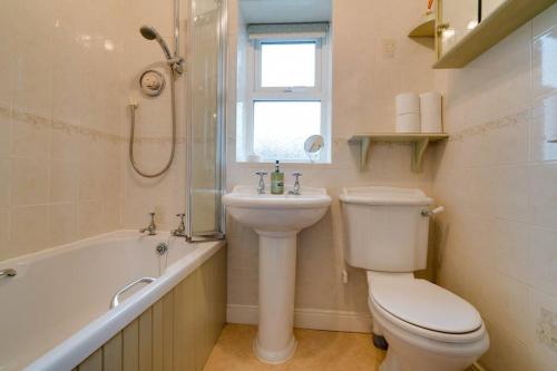 een badkamer met een toilet, een wastafel en een bad bij Barley Cottage in Whittington