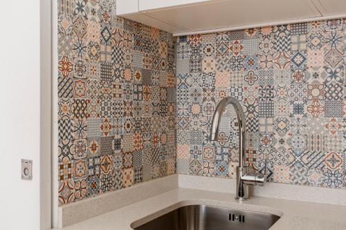 a kitchen with a sink and a tiled wall at Virtudes Flat w/ AC & Balcony by LovelyStay in Porto