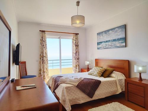 a bedroom with a bed and a desk and a window at MCStylo-Ocean View in Caniço