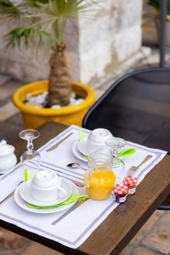 a table with a white table cloth with plates and glasses at Hotel les Armoiries in Valbonne