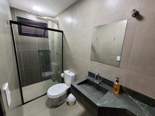 a bathroom with a toilet and a sink and a shower at Pousada Jardim do Lago in Cascavel