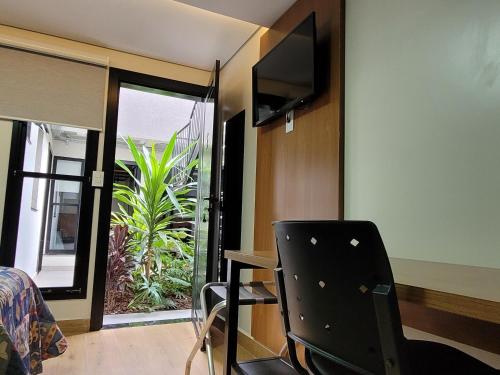 a room with a bed and a chair and a television at Pousada Jardim do Lago in Cascavel