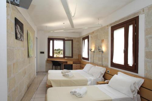 una camera d'albergo con 2 letti e una scrivania di Hotel Delle Cave a Favignana