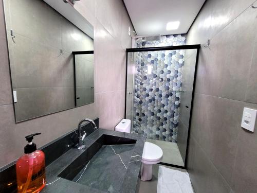 a bathroom with a shower and a sink and a toilet at Pousada Jardim do Lago in Cascavel