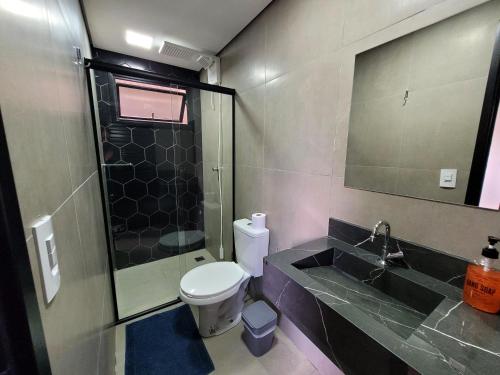 a bathroom with a toilet and a shower and a sink at Pousada Jardim do Lago in Cascavel