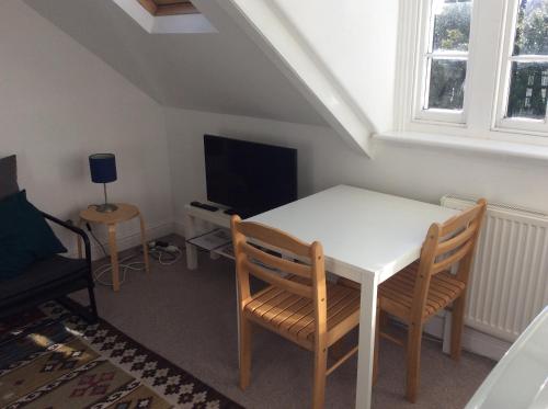 a room with a white table and chairs and a tv at Cosy Loft Apartment in Georgian Home in Plymouth