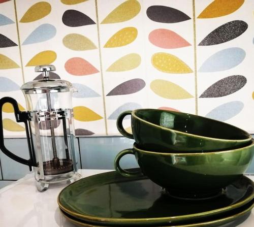 a green bowl on a plate next to a blender at Garden Apartment Morpeth- with lockable bike storage! in Morpeth