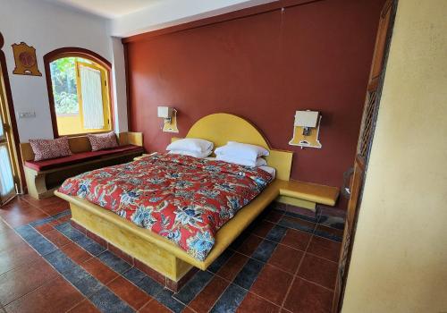 a bedroom with a bed with a red wall at Casa Anjuna in Anjuna
