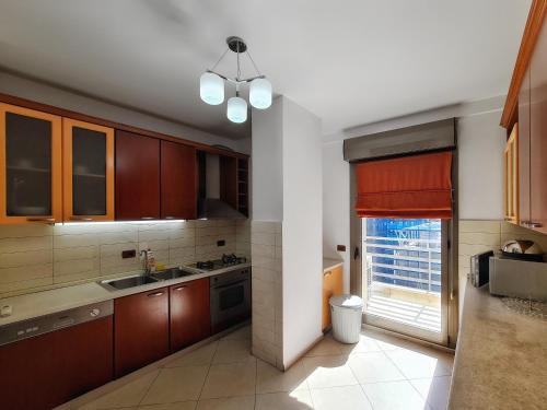 una cocina con armarios de madera y una gran ventana en Rino's Apartment, en Tirana