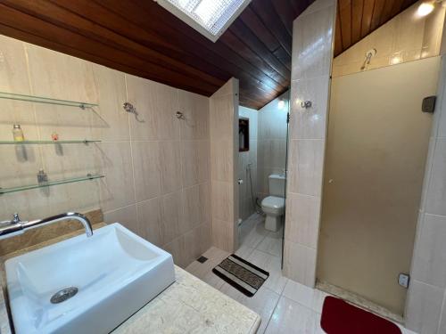 uma casa de banho com um lavatório, um chuveiro e um WC. em Casa com vista deslumbrante próximo a feirinha em Teresópolis