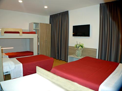 a hotel room with two beds and a flat screen tv at Sempione Hotel Malpensa in Casorate Sempione